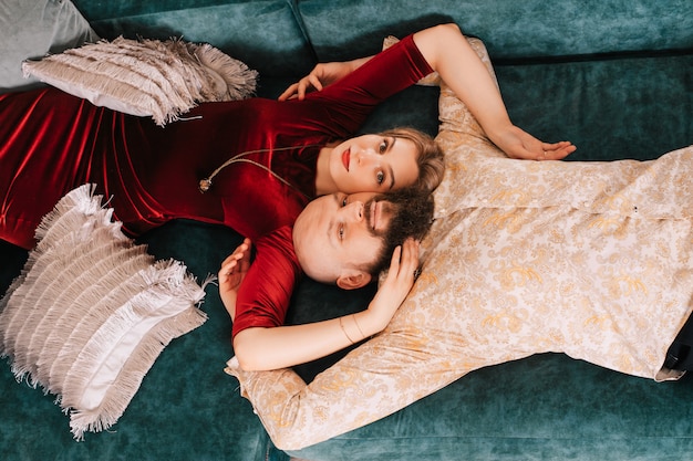 Beautiful couple in love lying on the couch. Beautiful people. Man and woman close-up, top view. Beautiful blonde girl and bearded man hugging each other