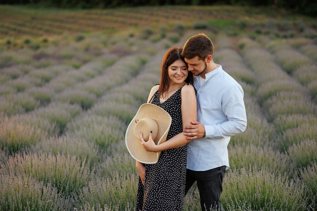 Beautiful couple of man and woman hugging while standing in the middle of lavender field