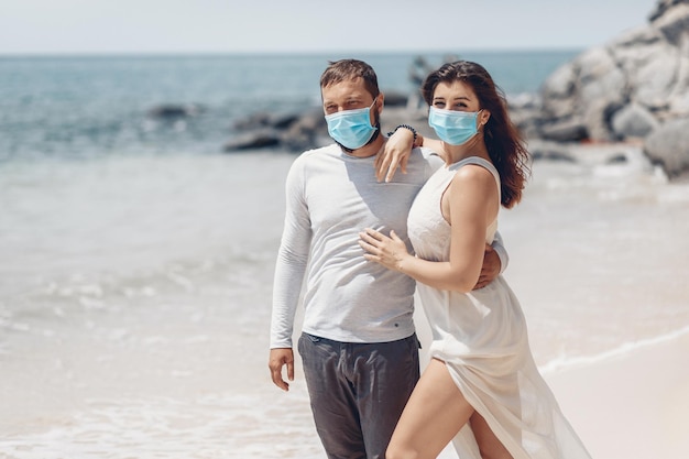 Beautiful couple for personal hygiene purposes putting medical masks on their faces to protect themselves from a coronavirus infection. COVID-19 concept