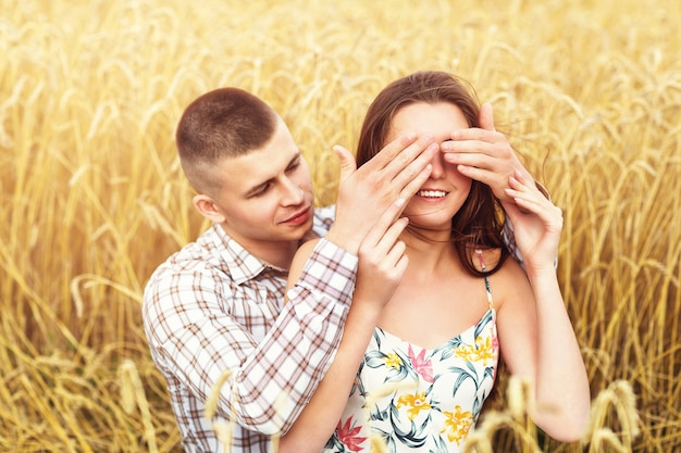 Beautiful couple resting on a wheat field loving girl and her boyfriend together