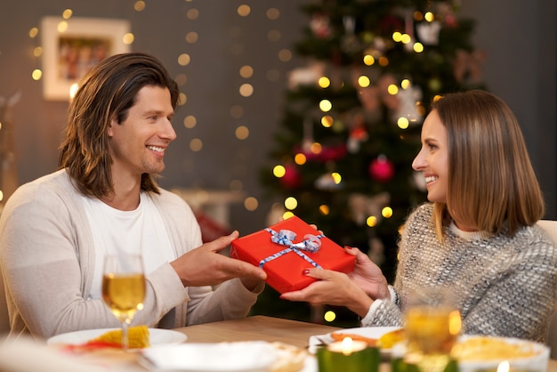 Beautiful couple sharing presents during Christmas dinner