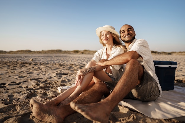 Beautiful couple sitting at the beach watching the sunset