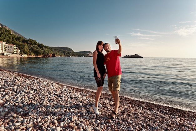 beautiful couple taking a selfie by the sea