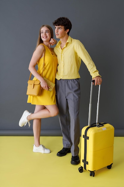 Beautiful couple with travel bag standing in studio