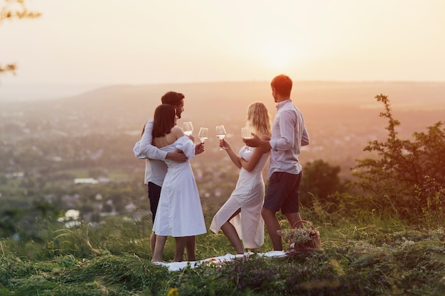 Beautiful couples standing on the hill at picnic at sunset