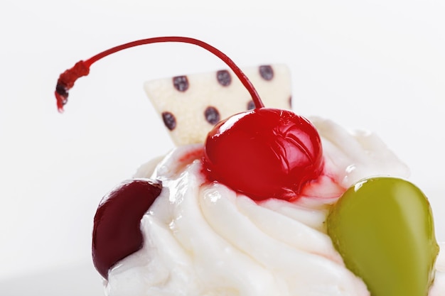 Beautiful cream cakes with cherries and grapes on a plate on a white background closeup