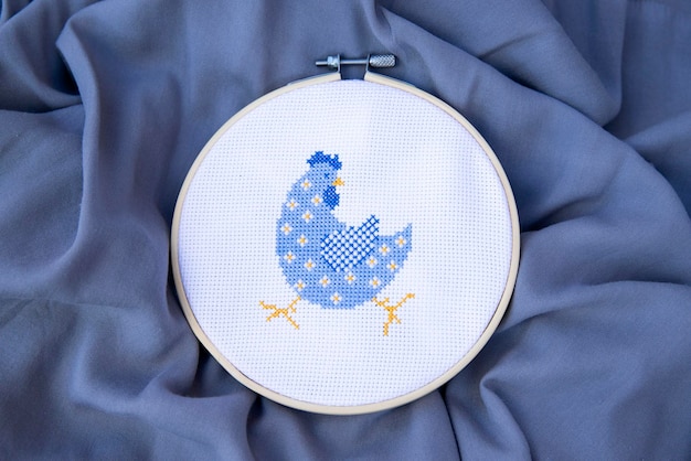 Photo a beautiful crossstitched blue cockerel in a flower embroidered bird on fabric