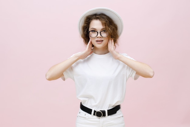 Beautiful curlyhaired girl in white casual clothes hat and glasses