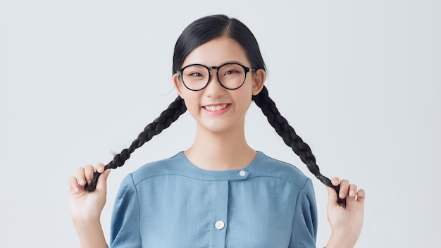 Beautiful cute girl having fun and holding pigtails posing near white wall