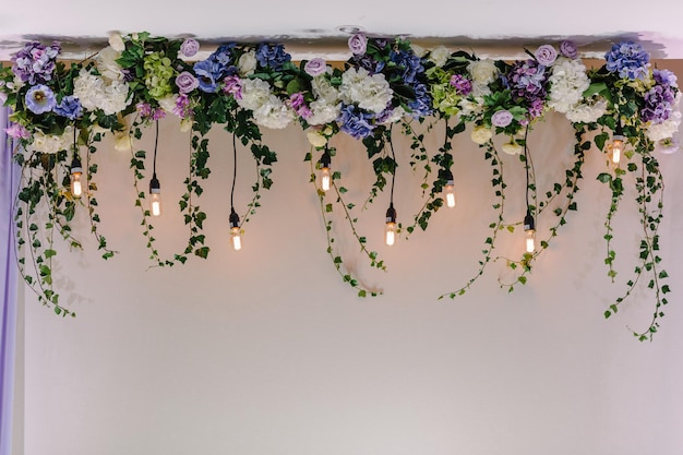 Beautiful decor made with garland with luminous lamps and floral decorations Decor of flowers on wedding ceremonyxA