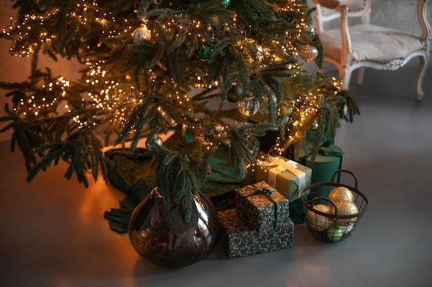 Beautiful decorated Christmas tree with gifts and lights glowing garlands in living room