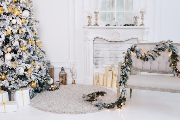 Beautiful decorated golden Christmas tree in luxury white classic interior with fireplace and sofa.