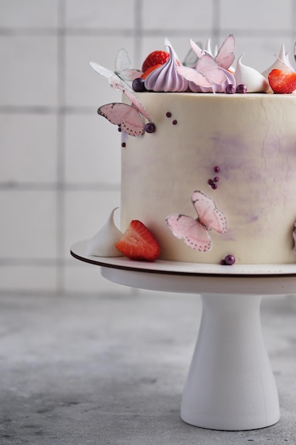 Beautiful and delicate strawberry cake for a girl. Dessert is decorated with fresh strawberries, meringues and butterflies.