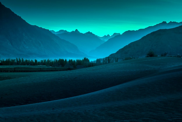 Beautiful desert and sand landscape with stunning mountain background on blue and green sky