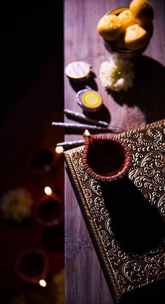 Photo beautiful diwali diya with fire crackers and sweet pera, selective focus