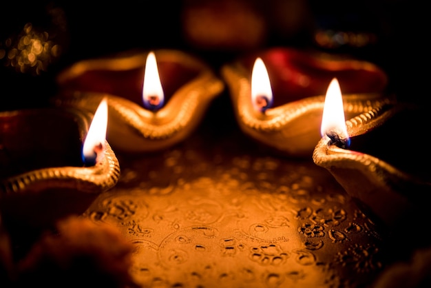 Beautiful Diwali diyas at night with flowers, lighting series and gifts, moody scene