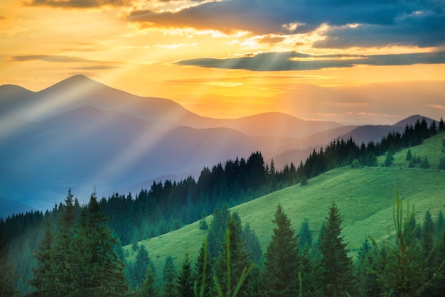 Beautiful dramatic sunset in the mountains. Landscape with sun shining through orange clouds