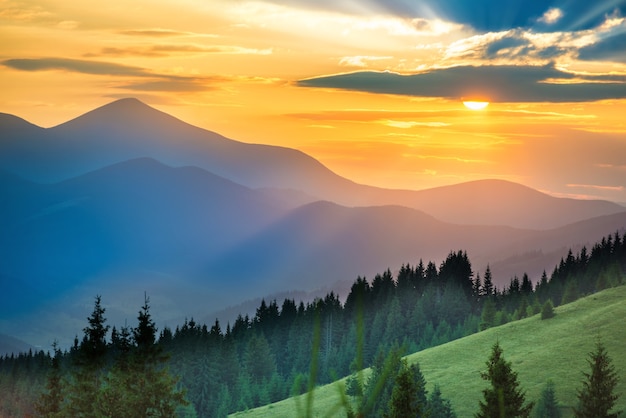 Beautiful dramatic sunset in the mountains. Landscape with sun shining through orange clouds