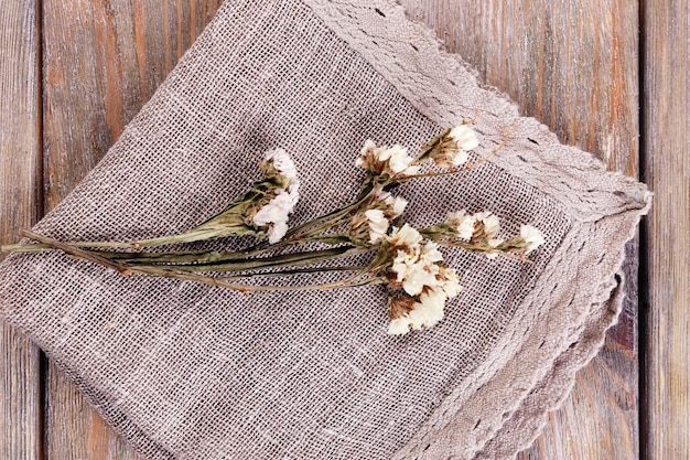 Beautiful dry flowers on napkin on wooden table close up