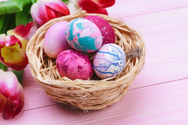 Beautiful Easter composition with decorated eggs and flowers on pastel wooden  