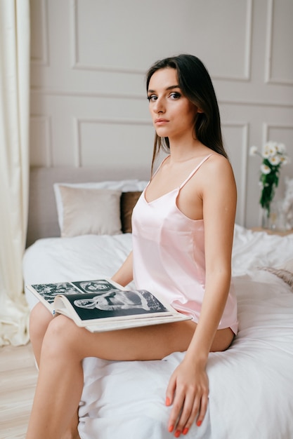 Beautiful elegant girl sitting  in bed with book