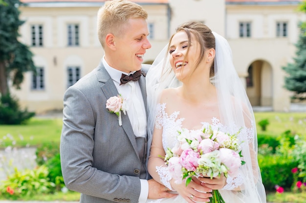 Beautiful elegant newlyweds hugging on the street on a summer day Wedding couple concept