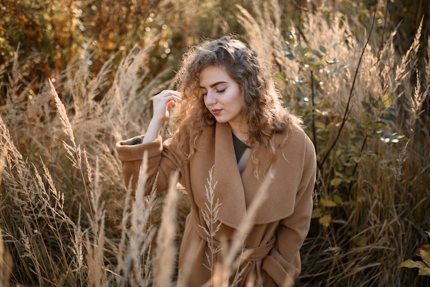 Beautiful elegant woman standing in a park in autumn