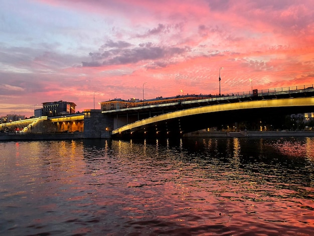 Beautiful embankment during sunset sunset on the river illuminated bridge across the river