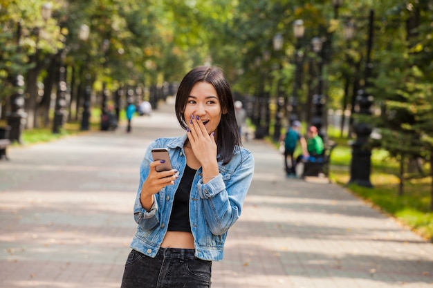 Beautiful emotional Asian girl with a smartphone in her hands. Surprise