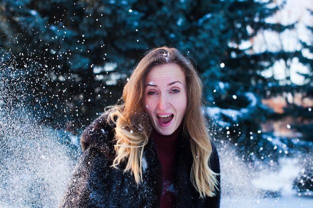 The beautiful emotional woman under the snow, after flying snowball