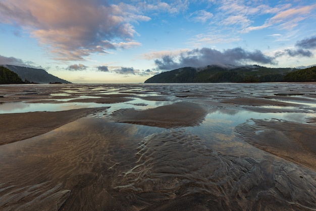 Beautiful empty beach with dramatic clouds and tide ripples going out in the sand.