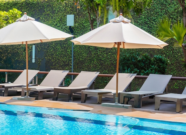 Beautiful empty chair with umbrella around outdoor swimming pool in hotel resort for vacation travel