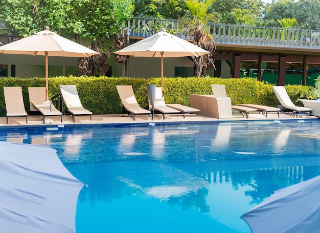 Beautiful empty chair with umbrella around outdoor swimming pool in hotel resort for vacation travel