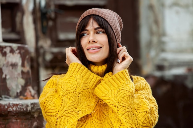 Beautiful European brunette dressed in a yellow woolen sweater and hat outside