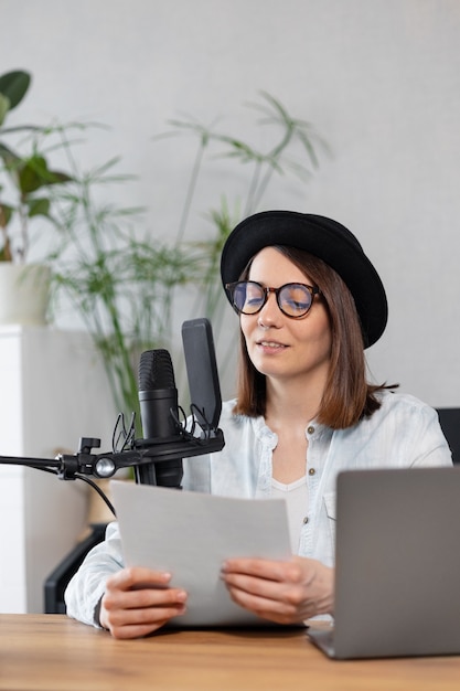 Beautiful european woman podcaster with headphones and microphone records podcast in recording