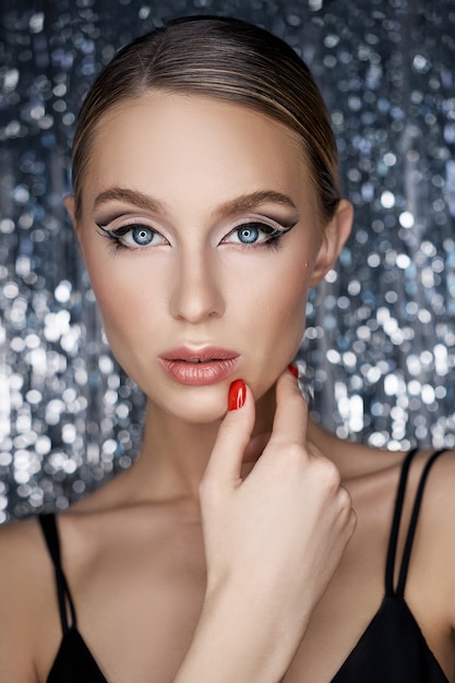 Beautiful evening eye makeup of a blonde woman on a shiny background. Close-up portrait of a woman, perfect eye makeup, skin care