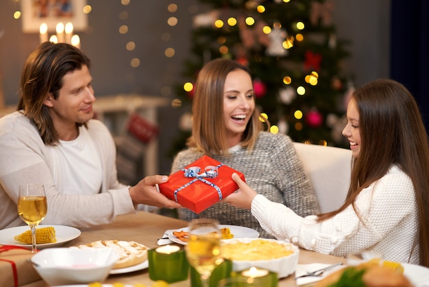 Beautiful family with presents sharing presents during Christmas dinner