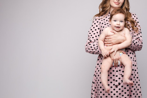 A beautiful family with a small child in the studio on a gray background