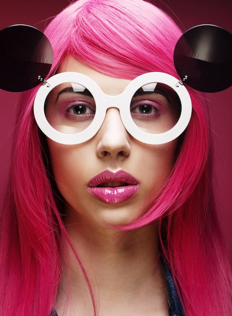 Beautiful fashion model  with pink hair and make-up wearing big sunglasses