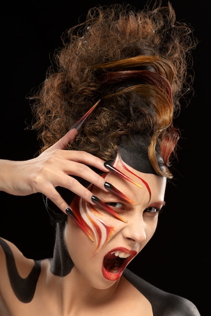 Beautiful fashion woman color face art fenix style and nail design. Aggressive emotion.