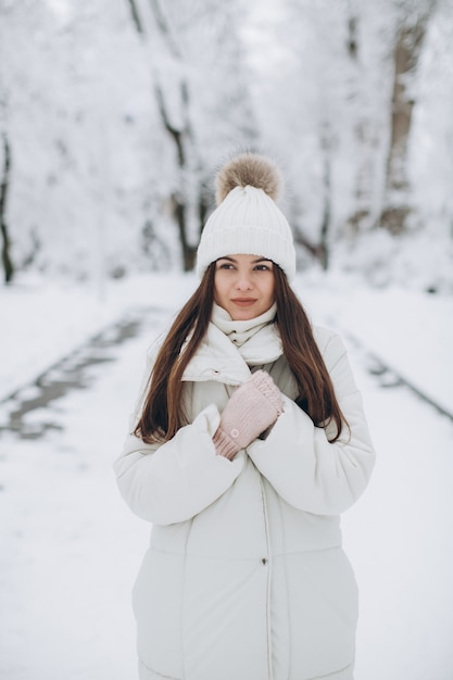 A beautiful and fashion woman in white warm clothing walking in snowy weather.