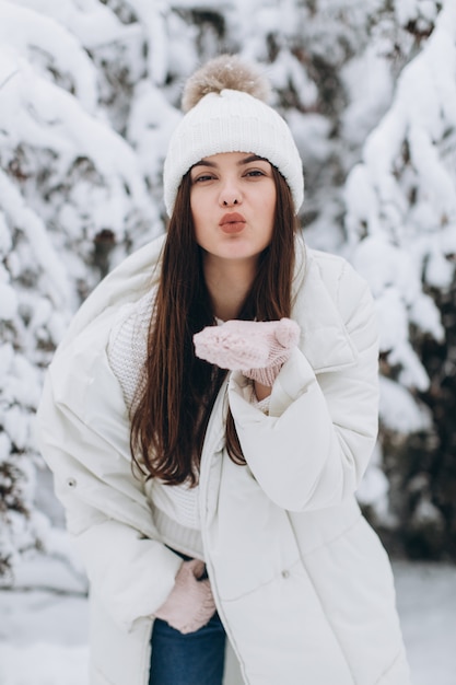 A beautiful and fashion woman in white warm clothing walking in snowy weather.