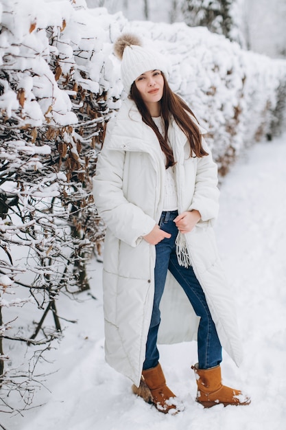 A beautiful and fashion woman in white warm clothing walking in snowy weather.