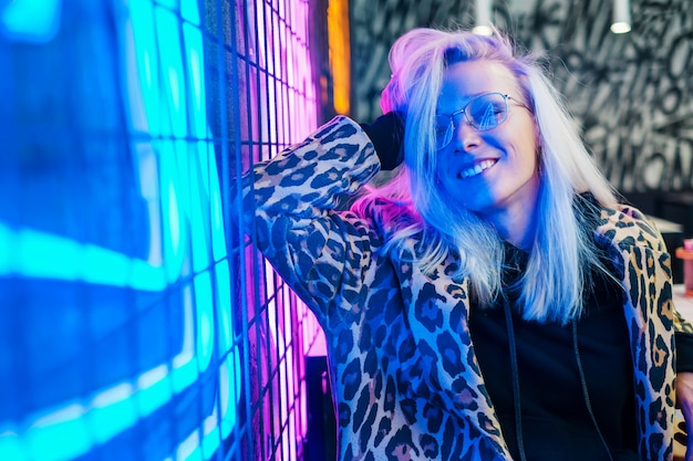 Beautiful fashionable girl sitting in bar near the neon wall