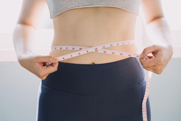 Beautiful fat woman with tape measure She uses her hand to squeeze the excess fat that is isolated on a white background She wants to lose weight the concept of surgery and break down fat under the