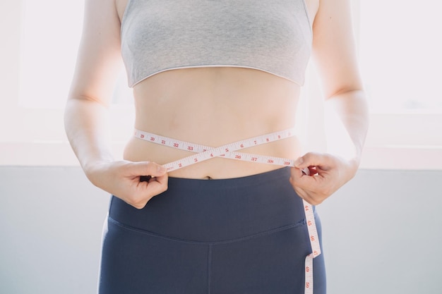 Beautiful fat woman with tape measure She uses her hand to squeeze the excess fat that is isolated on a white background She wants to lose weight the concept of surgery and break down fat under the