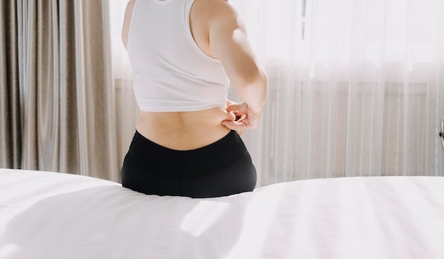 Beautiful fat woman with tape measure She uses her hand to squeeze the excess fat that is isolated on a white background She wants to lose weight the concept of surgery and break down fat under the