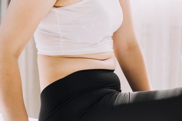 Beautiful fat woman with tape measure She uses her hand to squeeze the excess fat that is isolated on a white background She wants to lose weight the concept of surgery and break down fat under the