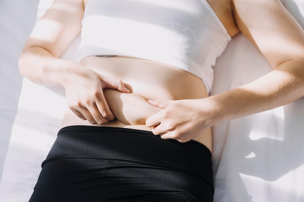 Beautiful fat woman with tape measure She uses her hand to squeeze the excess fat that is isolated on a white background She wants to lose weight the concept of surgery and break down fat under the