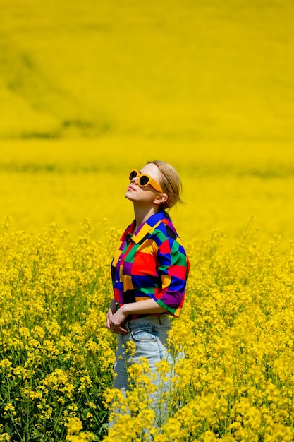 Beautiful female in 90s stylish shirt in rapeseed field